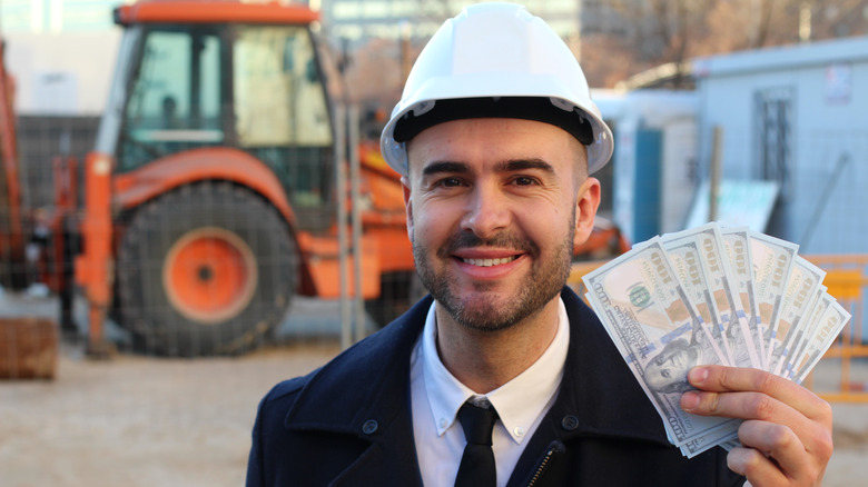 Construction foreman holding lots of US bills