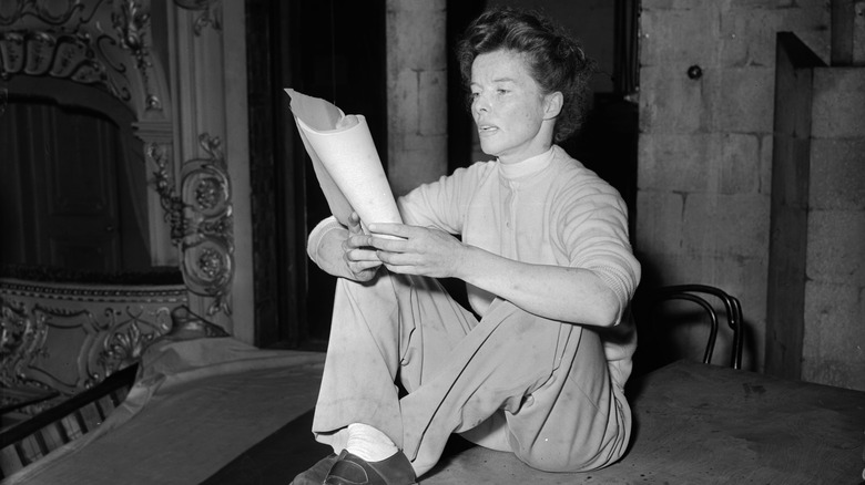 Katharine Hepburn seated, in pants