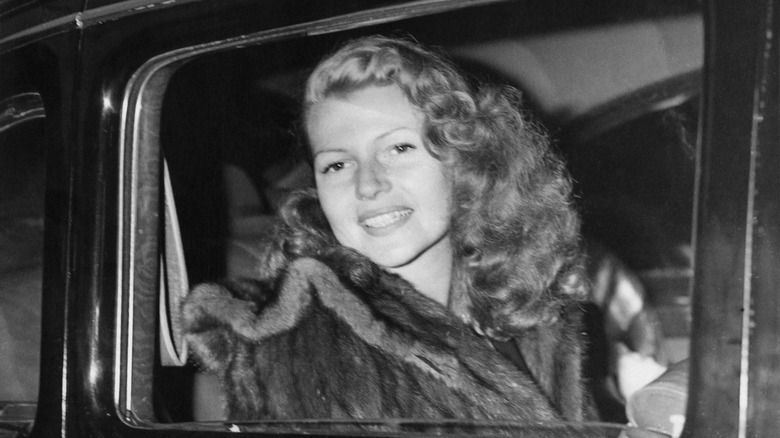 Rita Hayworth smiling in car