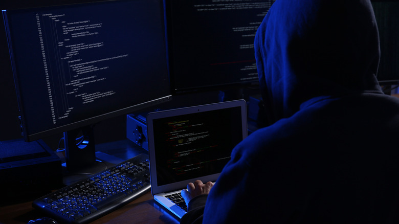 Hacker at laptop with code