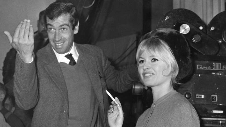 Roger Vadim waving, standing next to Brigitte Bardot