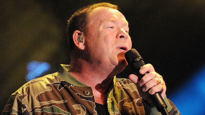 Ali Campbell of UB40 singing on stage in 2017