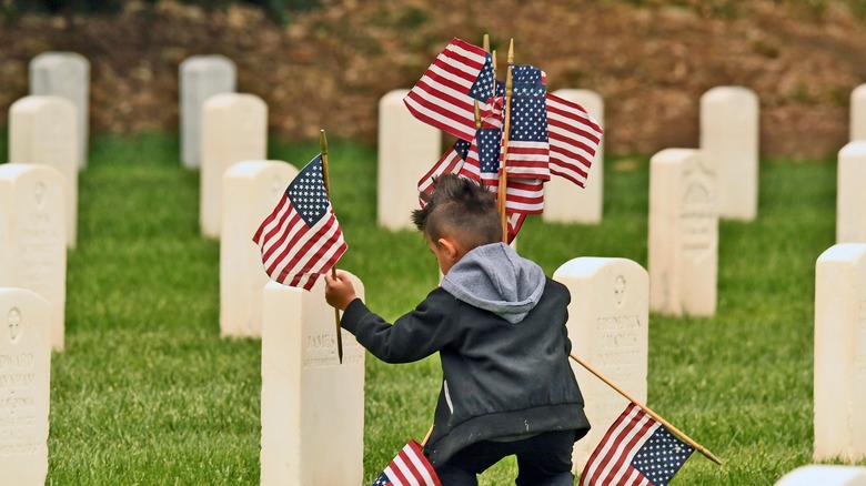 Boy placing flags on graves