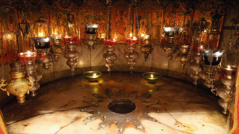 Silver star/Jesus' birth spot surrounded by candles