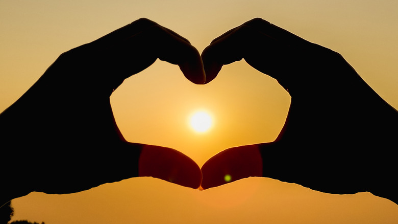 hands around sun to make heart shape