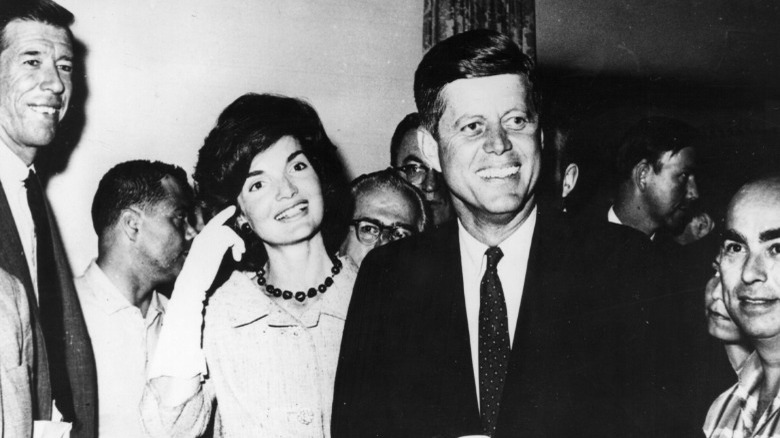 John F. Kennedy and Jackie Kennedy smiling in crowd