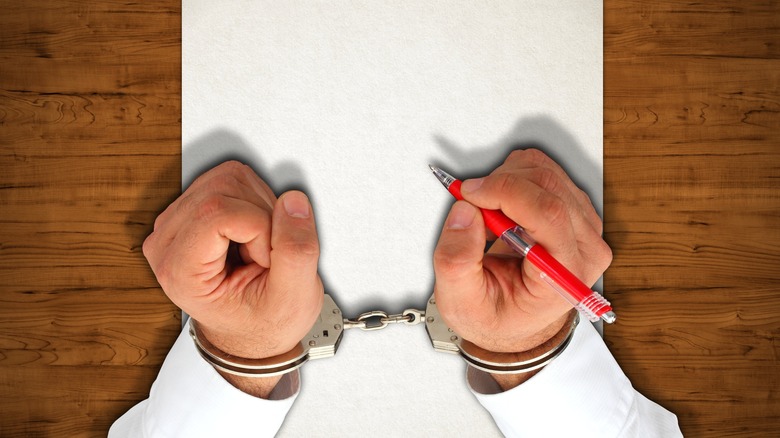 Man in handcuffs with pen and paper