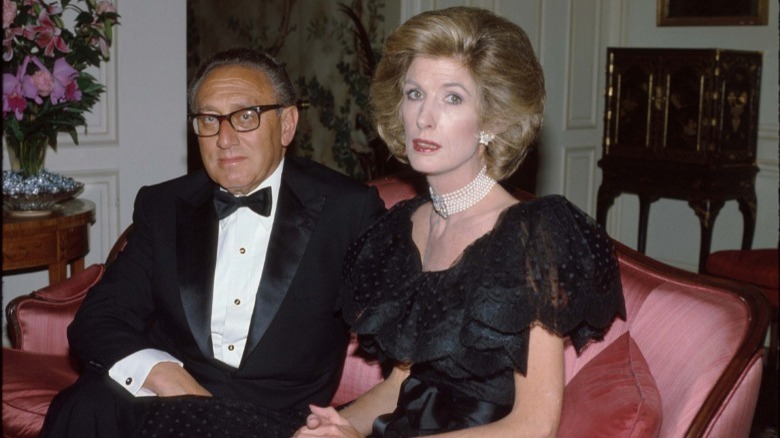Kissinger sitting on couch with and wife