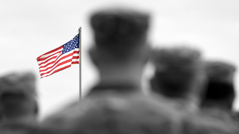 soldiers stand before a flag