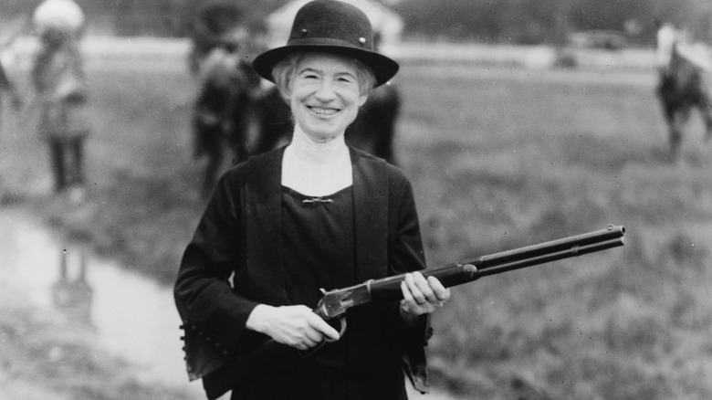 Smiling Annie Oakley holding a rifle