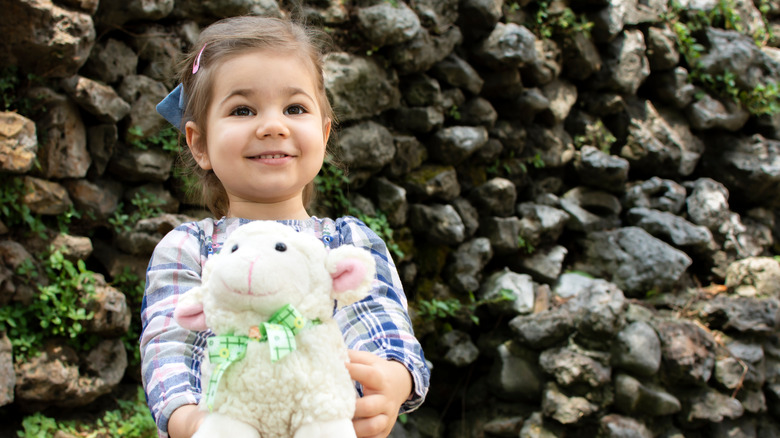 little girl holding a toy lamb