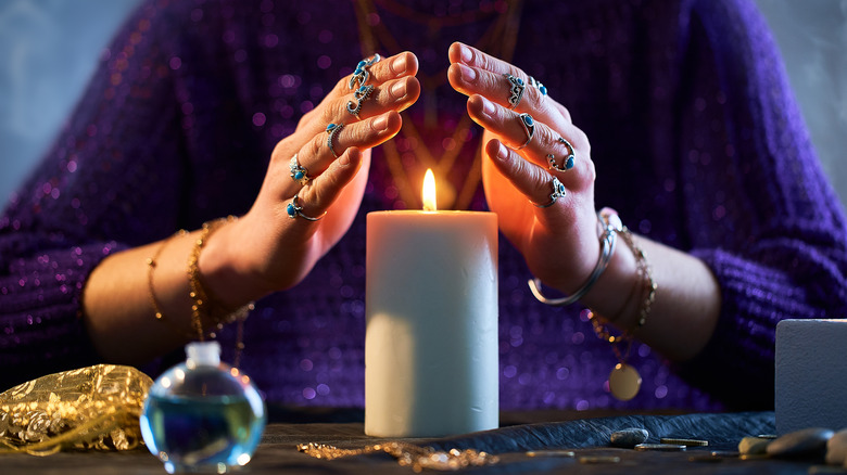 person holding hands above candle