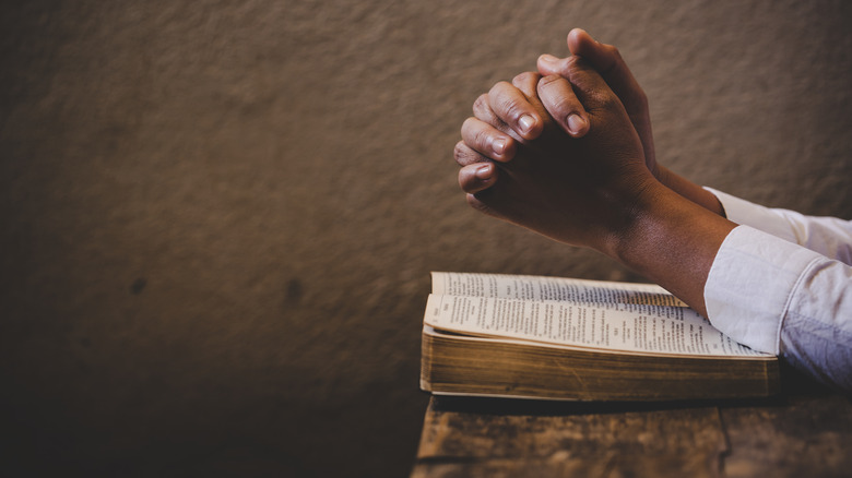 Praying hands over a bible