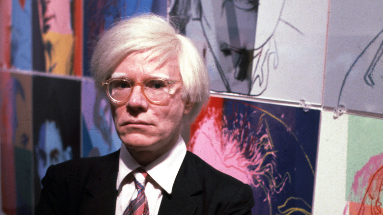 Andy Warhol posing with art