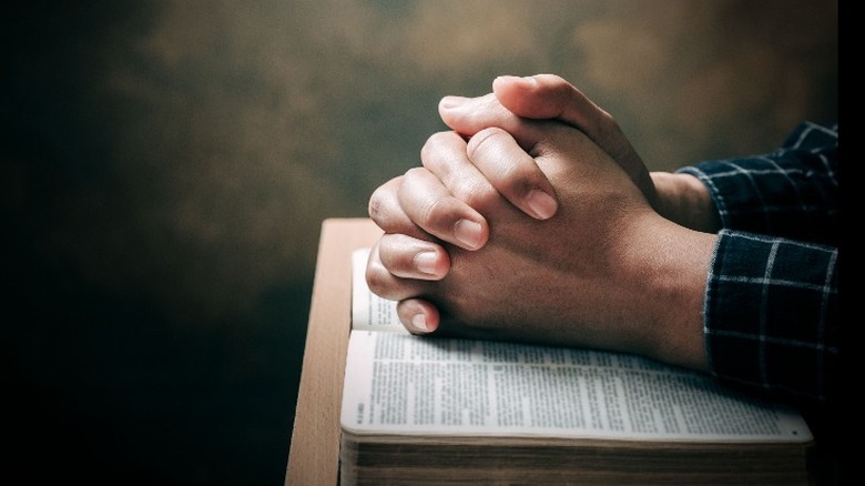 man's hands clasped over bible
