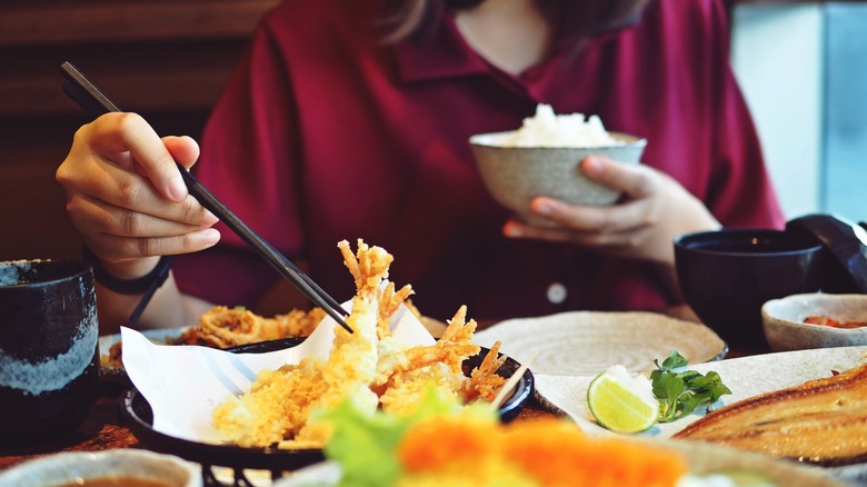 Woman eating rice and tempura with chopsticks