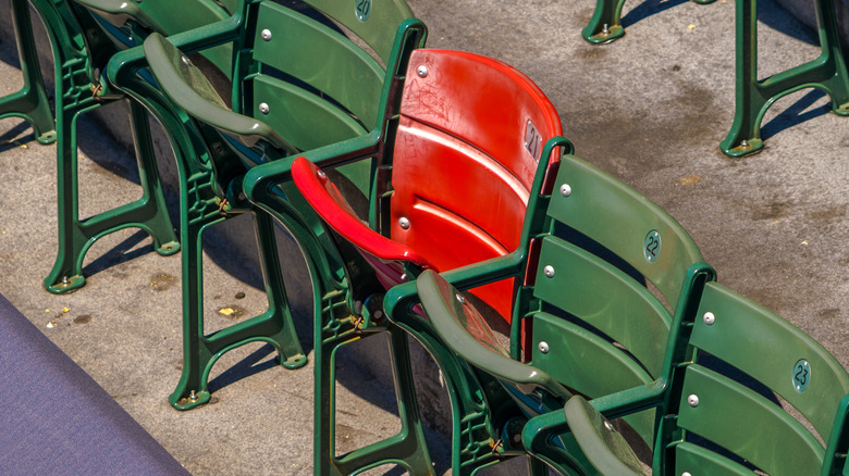 One red bleacher seat among green
