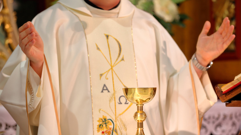 Priest with arms open in service