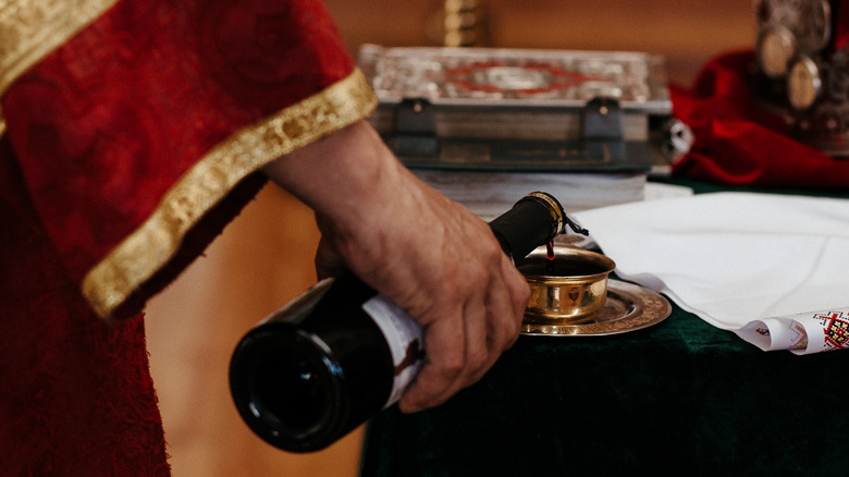 priest pouring wine